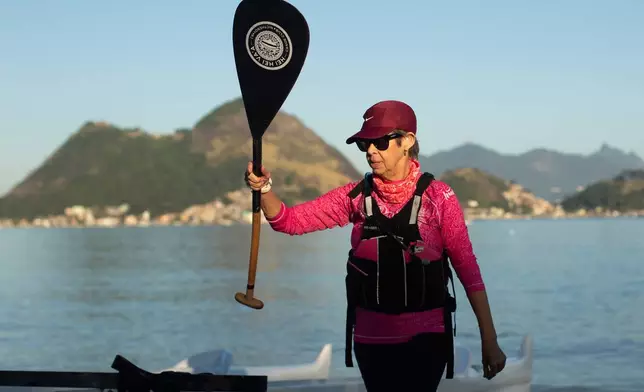 Breast cancer survivor Anna Lucia Amorim, 63, of the Rosas Va'a Hawaiian canoeing team whose members have undergone cancer treatment, gets ready for team training on Charitas Beach in Niteroi, Rio de Janeiro state, Thursday, June 26, 2025. (AP Photo/Bruna Prado)