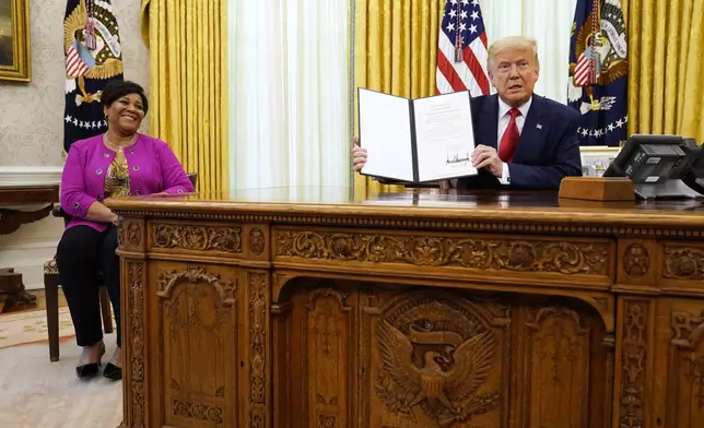 FILE - President Donald Trump holds up a full pardon for Alice Marie Johnson, left, in the Oval Office of the White House on Friday, Aug. 28, 2020. (AP Photo/Evan Vucci, File)