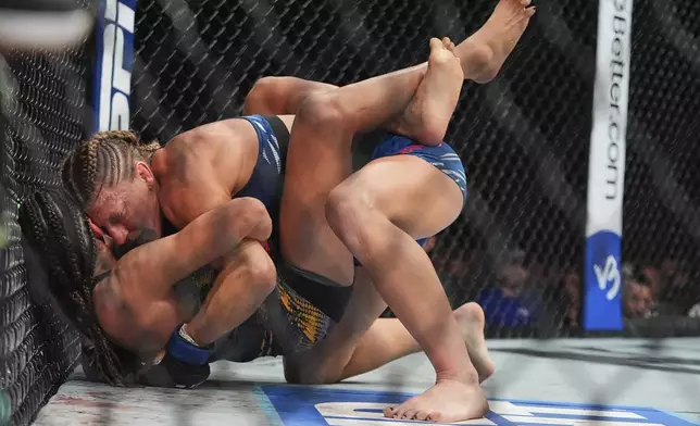 Kayla Harrison, right, grapples with Julianna Peña during the second round of a women's bantamweight bout at the UFC 316 mixed martial arts event Sunday, June 8, 2025 in Newark, N.J. (AP Photo/Frank Franklin II)