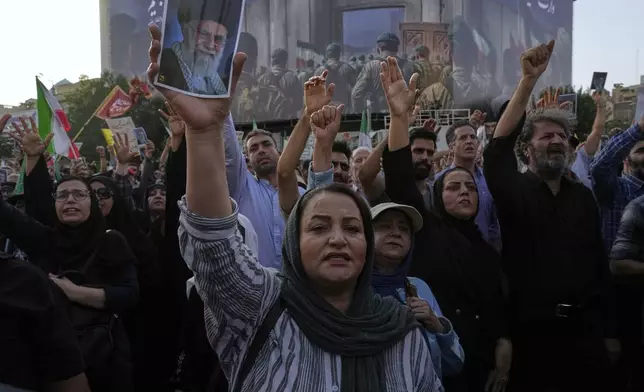 Protesters chant slogans as one of them holds up a poster of the Iranian Supreme Leader Ayatollah Ali Khamenei in a protest following the U.S. attacks on nuclear sites in Iran, in Tehran, Iran, Sunday, June 22, 2025. (AP Photo/Vahid Salemi)