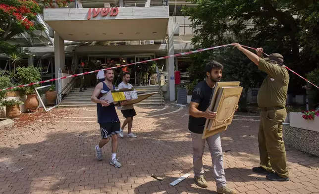 People recover items from a building damaged in an Iranian missile strike in Tel Aviv, Israel, Sunday, June 22, 2025. (AP Photo/Bernat Armangue)