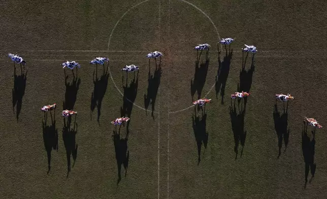 Moorish knights, in red, and Christian knights, in blue, ride horses during a battle reenactment at the Cavalhadas, or Holy Spirit, Festival in Pirenopolis, Goias state, Brazil, Monday, June 9, 2025. (AP Photo/Eraldo Peres)