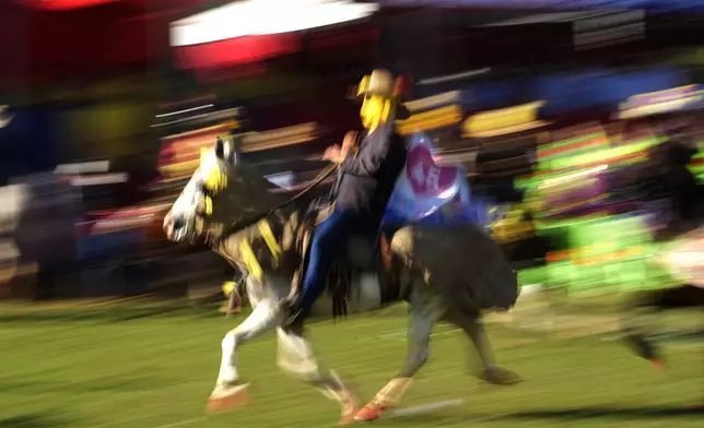 A masked reveler rides a horse during in the Cavalhadas, or Holy Spirit, Festival in Pirenopolis, Goias state, Brazil, Sunday, June 8, 2025. (AP Photo/Eraldo Peres)
