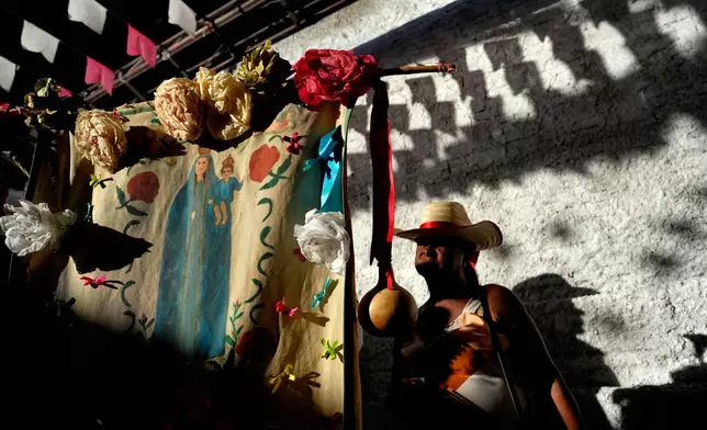 A reveler stands behind the flag of Our Lady of the Rosary at the Cavalhadas, or Holy Spirit, Festival, in Pirenopolis, Goias state, Brazil, Sunday, June 8, 2025. (AP Photo/Eraldo Peres)