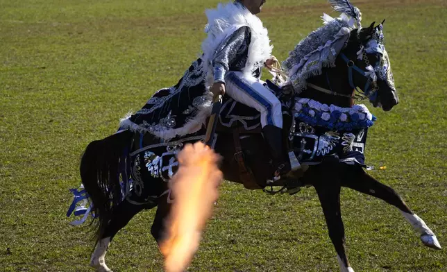 A Christian knight fires a gun during a battle reenactment at the Cavalhadas, or Holy Spirit, Festival in Pirenopolis, Goias state, Brazil, Monday, June 9, 2025. (AP Photo/Eraldo Peres)