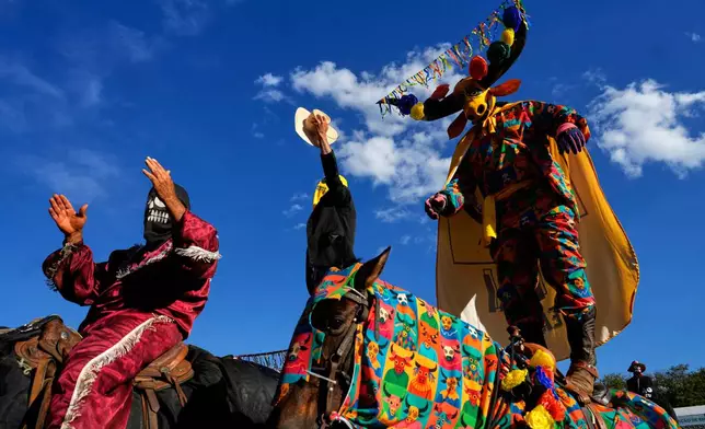 Masked revelers celebrate the hymn of the Divine Holy Spirit during the Cavalhadas Festival in Pirenopolis, Goias state, Brazil, Sunday, June 8, 2025. (AP Photo/Eraldo Peres)