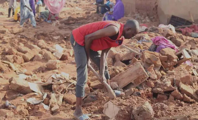 A man searches the rubble in a flooded area after heavy rainfall in the market town of Mokwa, north-central Nigeria, Saturday May 31, 2025. (AP Photo/Usman Salihu Mokwa)