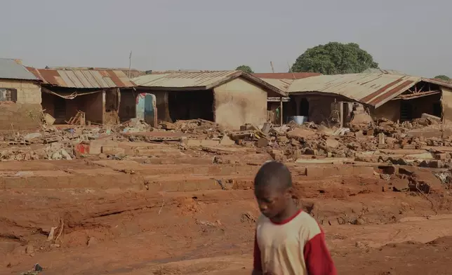 A boy walks past a flooded area after heavy rainfall in the market town of Mokwa, north-central Nigeria, Saturday May 31, 2025. (AP Photo/Usman Salihu Mokwa)