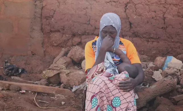 A woman sits in a flooded area after heavy rainfall in the market town of Mokwa, north-central Nigeria, Saturday May 31, 2025. (AP Photo/Usman Salihu Mokwa)