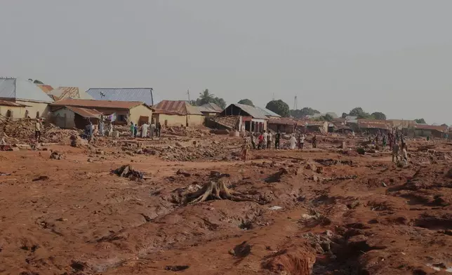 People gathered in a flooded area after heavy rainfall in the market town of Mokwa, north-central Nigeria, Saturday May 31, 2025. (AP Photo/Usman Salihu Mokwa)