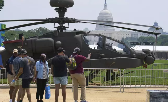People look at a military helicopter with the Capitol in the background, Friday, June 13, 2025, on the National Mall in Washington, during preparations for an upcoming military parade commemorating the Army's 250th anniversary and coinciding with President Donald Trump's 79th birthday. (AP Photo/Jacquelyn Martin)