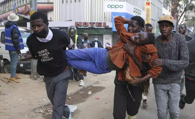 A woman overwhelmed by tear gas is carried away during a protest over the death of blogger Albert Ojwang in police custody, Thursday June 12, 2025, Nairobi, Kenya. (AP Photo/Andrew Kasuku)