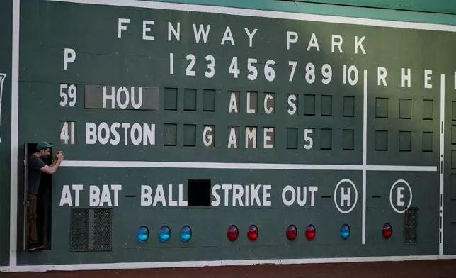 A scoreboard worker takes a picture before a game in this Oct. 20, 2021 file photo, in Boston. (AP Photo/Robert F. Bukaty)