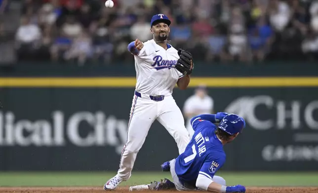Texas Rangers second base Marcus Semien turns a double play over Kansas City Royals' Bobby Witt Jr. to put out Maikel Garcia at first in the third inning of a baseball game, Thursday, June 19, 2025, Arlington, Texas. (AP Photo/Albert Pena)