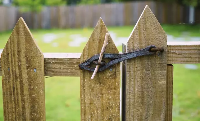A hand-forged hasp and wooden dowel guard the entrance to the burial ground at the First Baptist Church of Williamsburg in Williamsburg, Va., on May 30, 2025. (AP Photo/Allen G. Breed)