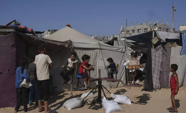 Displaced Palestinian children play at a tent camp on the first day of Eid al-Adha in Khan Younis, Gaza, Friday, June 6, 2025. (AP Photo/Abdel Kareem Hana)