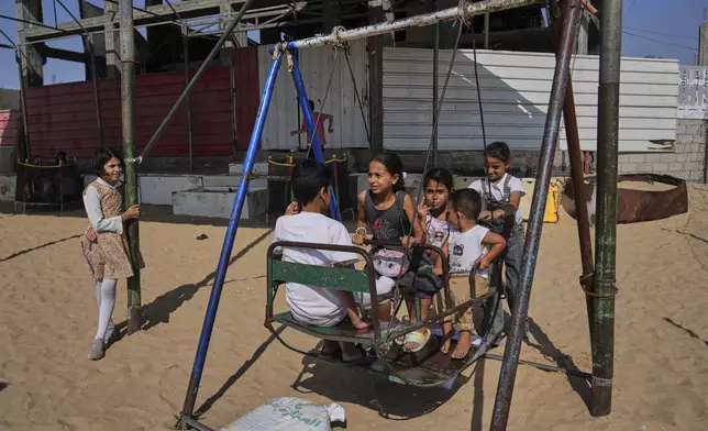 Displaced Palestinian children play on a swing at a tent camp on the first day of Eid al-Adha in Khan Younis, Gaza, Friday, June 6, 2025. (AP Photo/Abdel Kareem Hana)