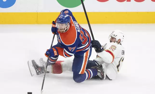 Florida Panthers' Sam Reinhart (13) and Edmonton Oilers' Connor McDavid (97) battle for the puck during the third period in Game 5 of the NHL hockey Stanley Cup Final in Edmonton, Alberta, Saturday, June 14, 2025. ( Jason Franson/The Canadian Press via AP)