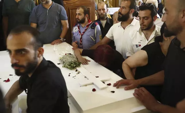 Mourners gather around the coffin of a victim of Sunday's suicide bombing at Mar Elias Greek Orthodox Church, during a funeral service held at al-Saleeb Church in the al-Qasaa neighborhood of Damascus, Syria, Tuesday, June 24, 2025. (AP Photo/Omar Sanadiki)
