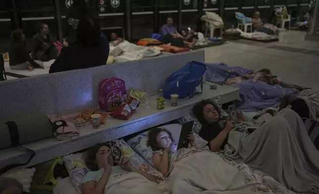People take shelter in an underground metro station as a precaution against possible Iranian missile attacks, in Ramat Gan, near Tel Aviv, Israel, Tuesday, June 17, 2025. (AP Photo/Oded Balilty)