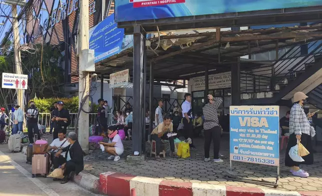 In this photo released by Royal Thai Army, peoples sit near a border checkpoint between Thailand and Cambodia, in Sa Kaeo Province, Thailand, Tuesday, June 24, 2025. (Royal Thai Army via AP)