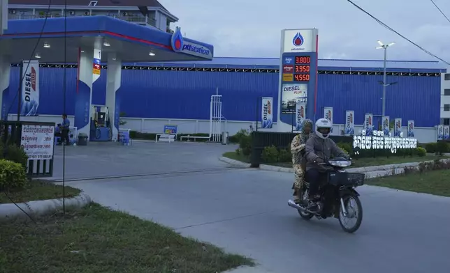 A couple rides on a motorcycle after filling gasoline at a PTT, (Petroleum Authority of Thailand), outside Phnom Penh, Cambodia, Monday, June 23, 2025. (AP Photo/Heng Sinith)