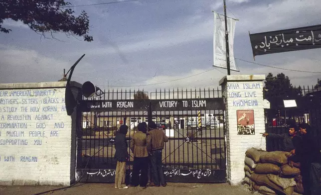 FILE - The entrance to the U.S. Embassy in Tehran, Iran, where 63 people are being held hostage, seen in 1980. Graffiti on the wall at left reads: "Dear American minority, brothers and sisters (Blacks and Indians) study the holy Koran and start a revolution against U.S. discrimination. God and Iranian Muslim people are supporting you. Down with Reagan." (AP Photo, File)