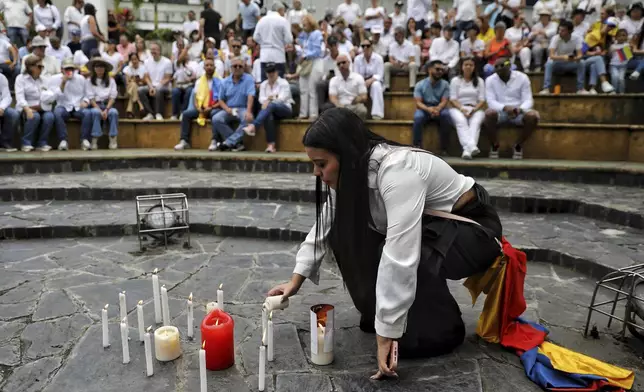 A woman lights a candle at a gathering to pray for Colombian Senator Miguel Uribe Turbay's recovery after he was shot at a political rally, in Cali, Colombia, Sunday, June 8, 2025. (AP Photo/Santiago Saldarriaga)