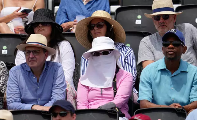 A spectator covers her face to keep cool in the stands during the match of the Queen's Club Championships tennis tournament in London, Friday, June 20, 2025. (AP Photo/Kin Cheung)