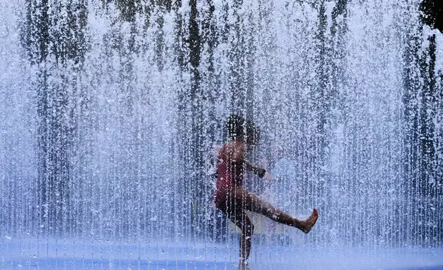 A child plays in a fountain in London, as a heatwave passes through the capital, Friday, June 20, 2025. (AP Photo/Kirsty Wigglesworth)
