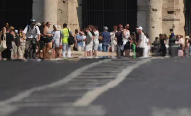 The summer heat creates an optical effect as tourists stand at the Colosseum in Rome, Friday, June 20, 2025. (AP Photo/Alessandra Tarantino)