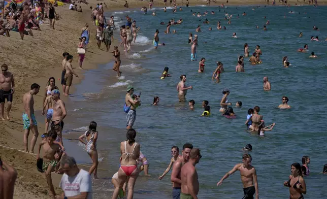 Swimmers cool off during high temperatures on a beach in Barcelona, Spain, Friday, June 20, 2025. (AP Photo/Emilio Morenatti)