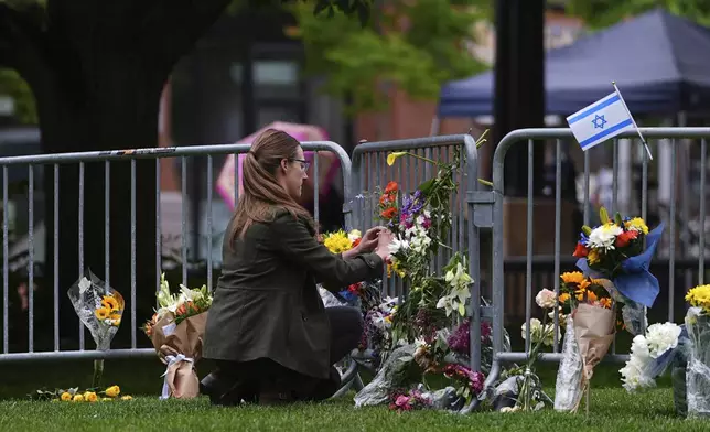 A woman places a bouquet of flowers at a makeshift memorial for victims of an attack outside of the Boulder County, Colo., courthouse Tuesday, June 3, 2025, in Boulder, Colo. (AP Photo/David Zalubowski)