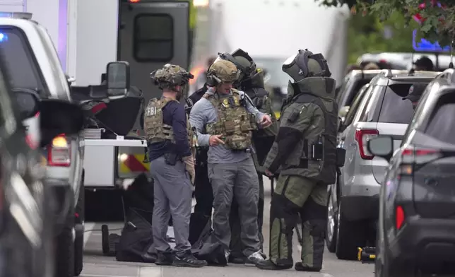 Law enforcement officials dress to investigate after an attack on the Peark Street Mall Sunday, June 1, 2025, in Boulder, Colo. (AP Photo/David Zalubowski)