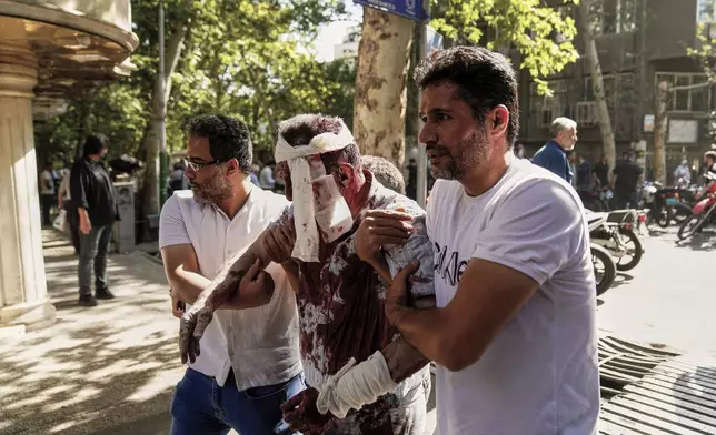 An injured man is helped to leave the scene after an explosion in downtown Tehran, amid Israel's three-day campaign of strikes against Iran, Sunday, June 15, 2025. (AP Photo/Amir Kholousi/ISNA)