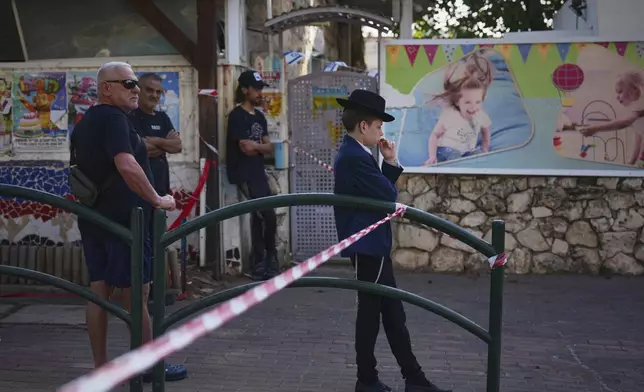 Residents look at the site where an Iranian missile struck in, Haifa, Israel, Monday, June 16, 2025. (AP Photo/Ariel Schalit)