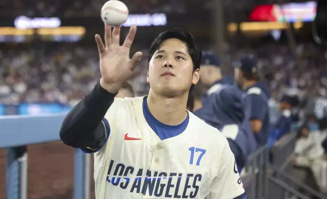Los Angeles Dodgers designated hitter Shohei Ohtani catches a ball in the dugout during the sixth inning of a baseball game against the Washington Nationals in Los Angeles, Saturday, June 21, 2025. (AP Photo/Jessie Alcheh)
