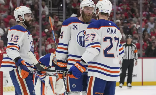 Edmonton Oilers defensemen Mattias Ekholm (14), Brett Kulak (27) and center Adam Henrique (19) talks during the second period of Game 3 of the NHL Stanley Cup final against the Florida Panthers Monday, June 9, 2025, in Sunrise, Fla. (AP Photo/Lynne Sladky)