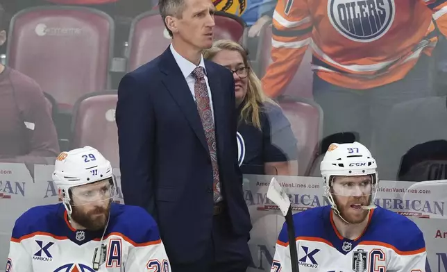 Edmonton Oilers head coach Kris Knoblauch looks on from the bench with Leon Draisaitl (29) and Connor McDavid (97) during the third period in Game 3 of the NHL hockey Stanley Cup finals against the Florida Panthers in Sunrise, Fla., Monday, June 9, 2025. (Nathan Denette/The Canadian Press via AP)