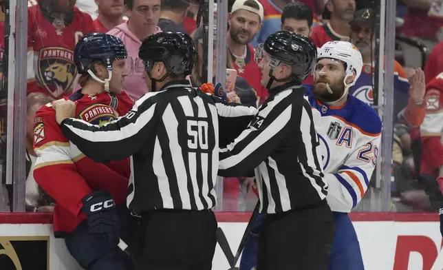 NHL referees separate Florida Panthers center Anton Lundell (15) and Edmonton Oilers center Leon Draisaitl (29) during the first period of Game 3 of the NHL Stanley Cup final Monday, June 9, 2025, in Sunrise, Fla. (AP Photo/Lynne Sladky)