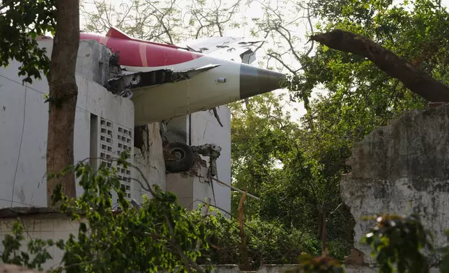 The tail of the airplane is seen stuck in a building at the site of an airplane that crashed in India's northwestern city of Ahmedabad in Gujarat state, Thursday, June 12, 2025. (AP Photo/Ajit Solanki)