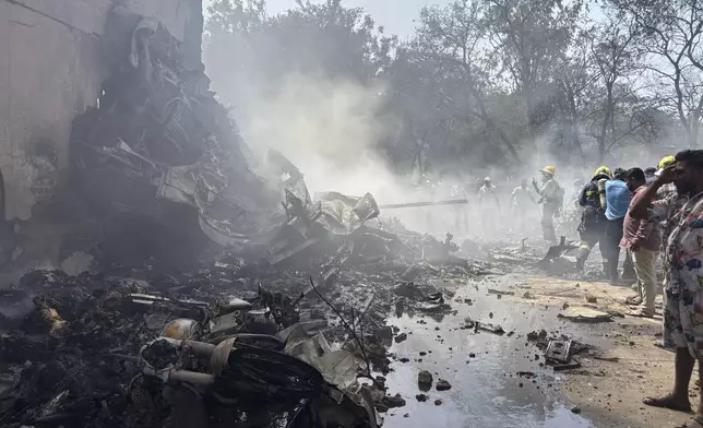 People stand around debris at the site of an airplane that crashed in India's northwestern city of Ahmedabad in Gujarat state, Thursday, June12, 2025. (AP Photo/Ajit Solanki)