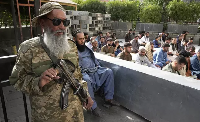 Afghan Muslims perform Eid al-Adha prayer while a Taliban fighter stands guard in the Shah-Do Shamshira Mosque in Kabul, Afghanistan, Saturday, June 7, 2025. (AP Photo/Ebrahim Noroozi)