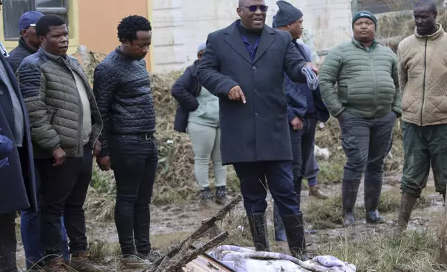 Eastern Cape premier Oscar Mabuyane, center, with local government officials stands in front of a recovered body after floods swept through the area, in Mthatha, South Africa, Wednesday, June 11, 2025. (AP Photo/Hoseya Jubase)