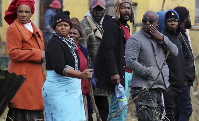 Community members and families watch as rescue workers recover bodies after floods swept through the area in Mthatha, South Africa, Wednesday, June 11, 2025. (AP Photo/Hoseya Jubase)