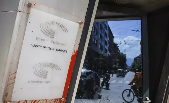 Street traffic is mirrored next to a damged sign of the EU Parliament and Commission in Sofia, Bulgaria, Monday, June 2, 2025. (AP Photo/Valentina Petrova)