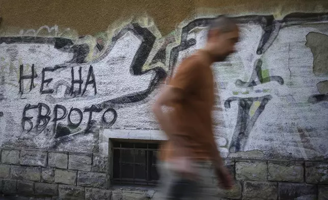 A man passes by graffiti sign reading 'No to Euro' in Sofia, Bulgaria, Monday, June 2, 2025. (AP Photo/Valentina Petrova)