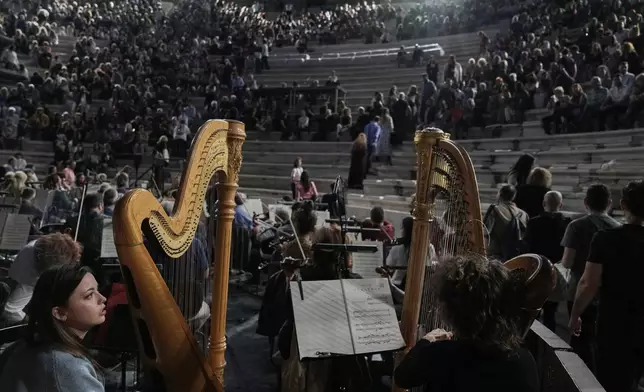 The two harpists of the Greek National Opera Ersilia Mikrou, left, and Anna Dermani watch the spectators taking their seats at the Odeon of Herodes Atticus ahead of Giacomo Puccini's "Turandot" dress rehearsal during the 70th Athens Epidaurus Festival in Athens, Greece, Friday, May 30, 2025. (AP Photo/Thanassis Stavrakis)