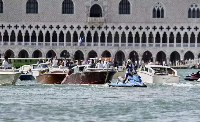ADDS INFORMATION THAT LAUREN SANCHEZ IS ON THE BOAT A police officer rides in front of the boat, center, carrying Lauren Sanchez as it travels past St. Mark's Square ahead of the anticipated wedding celebrations of Jeff Bezos and Lauren Sanchez, in Venice, Friday, June 27, 2025. (AP Photo/Luigi Costantini)