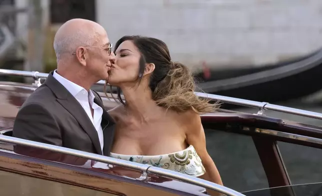 Jeff Bezos, left, and Lauren Sanchez kiss as they leave a hotel for their pre wedding reception, in Venice, Italy, Thursday, June 26, 2025. (AP Photo/Luca Bruno)